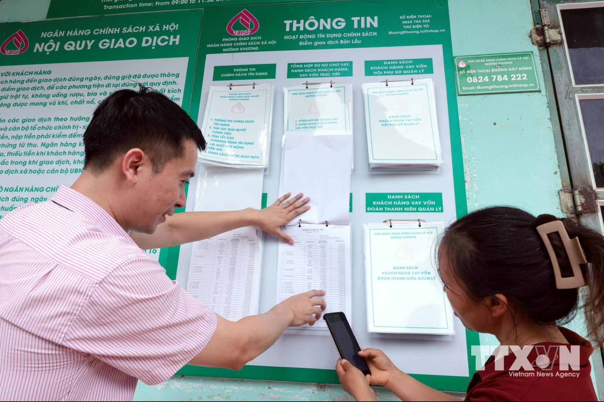 Tổ trưởng Tổ Tiết kiệm và vay vốn đối chiếu danh sách hộ vay được số hóa với danh sách niêm yết công khai tại điểm giao dịch xã Bản Lầu, Lào Cai. (Ảnh: Trần Việt/TTXVN)